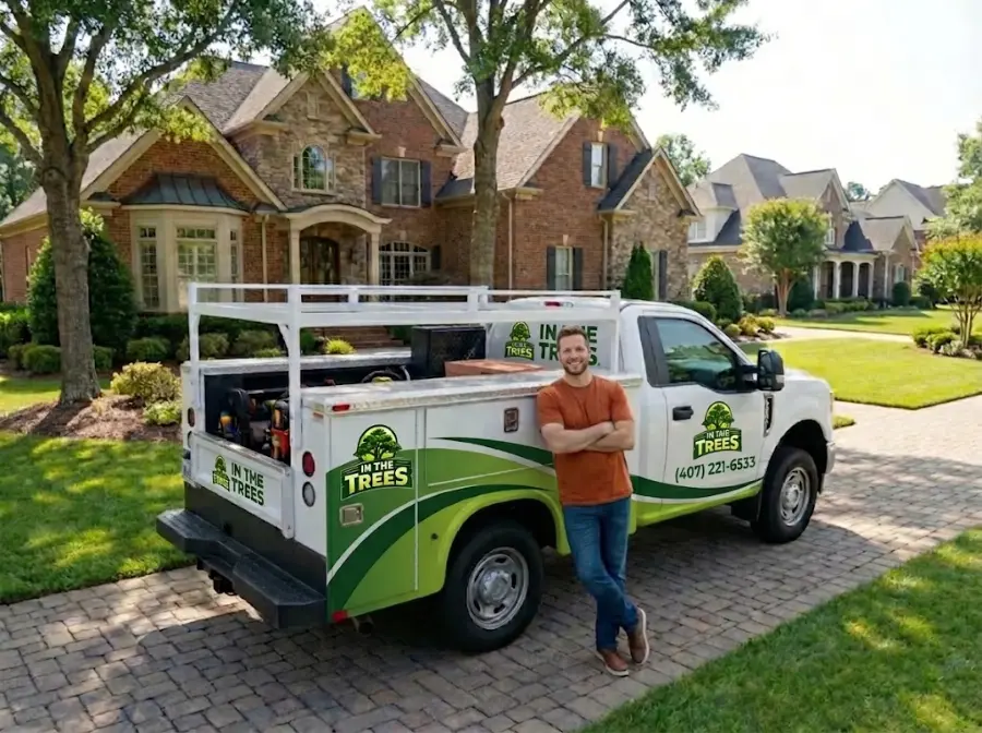 In The Trees team member leaning on the company work truck in a home's driveway